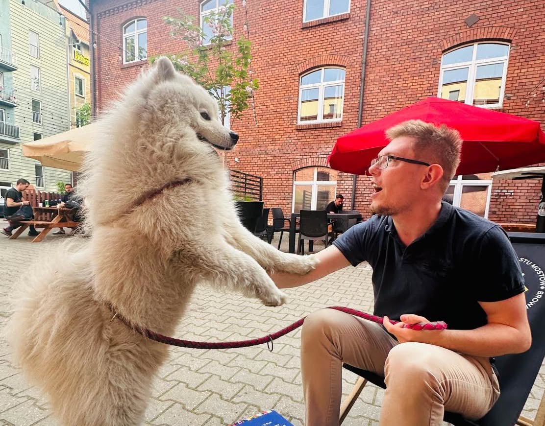 Bartosz Bednarczyk greeting a very fluffy white dog